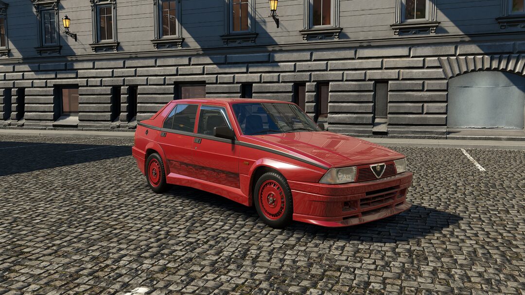 A red Alfa Romeo 75 Turbo Evoluzione photographed against an urban background in Assetto Corsa EVO Release 0.2. A motorsport-inspired turbocharged classic from the late '80s with aggressive styling and responsive performance.