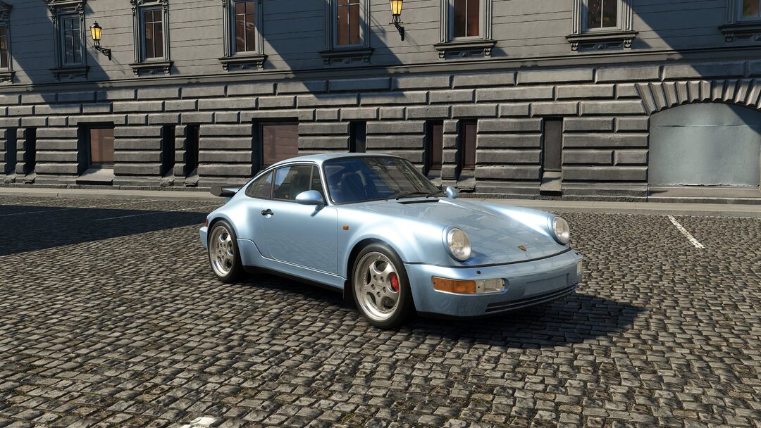 A sky blue Porsche 911 Turbo 3.6 [964] parked in an urban setting in Assetto Corsa EVO Release 0.2. A refined yet raw icon from the early '90s, delivering analog power through its 3.6-liter turbocharged engine.
